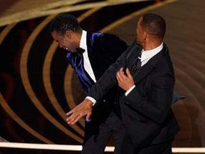 Will Smith, right, hits presenter Chris Rock during the Oscars