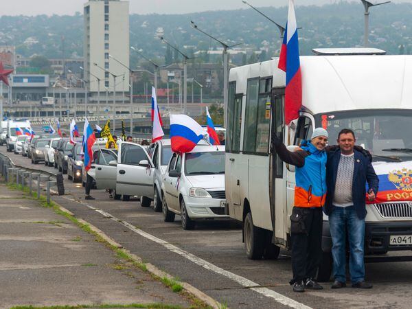 Two men pose for a photo in front of a motorcade organised to support voting in a Russian-backed referendum in Luhansk (AP Photo)