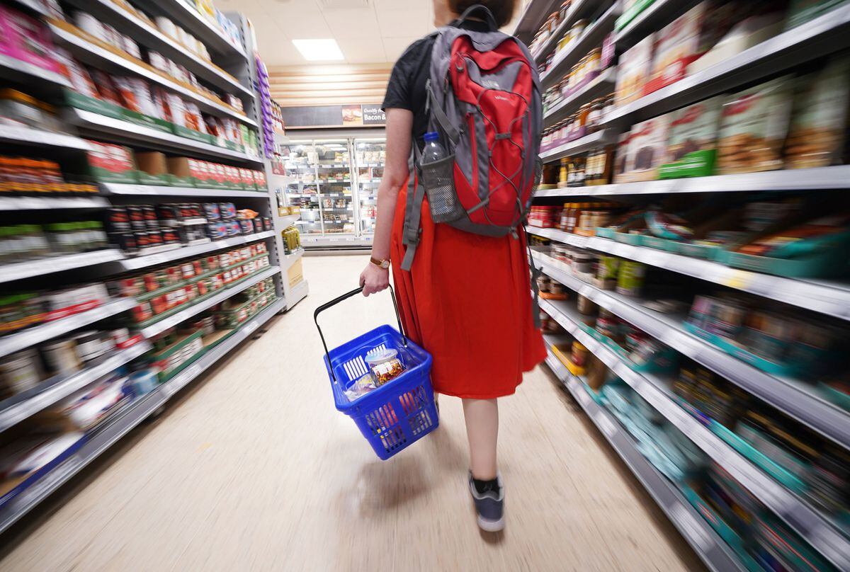A shopper walking through the aisle of a supermarket. 