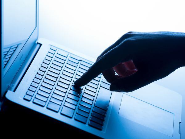 A woman’s hand pressing a laptop keyboard