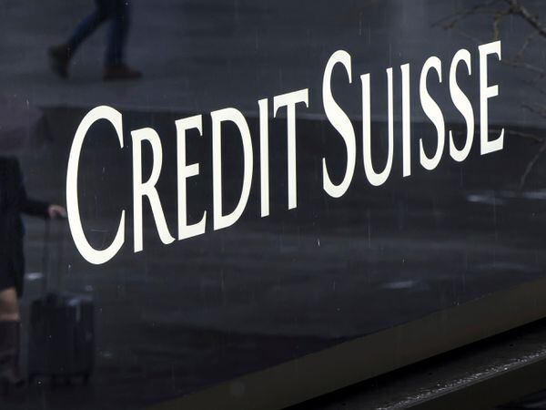 A woman walks past a logo of the Swiss bank Credit Suisse in Zurich