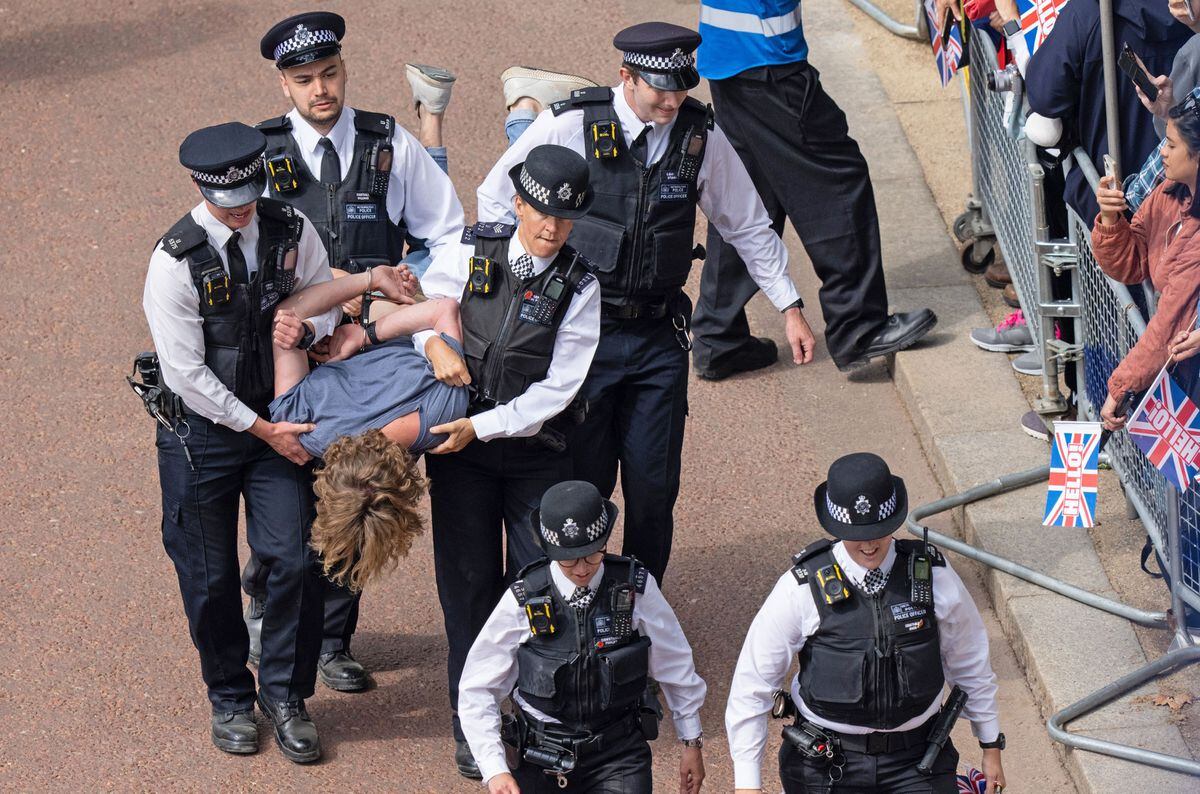 Police officers remove people who ran into the path of the royal procession on The Mall 
