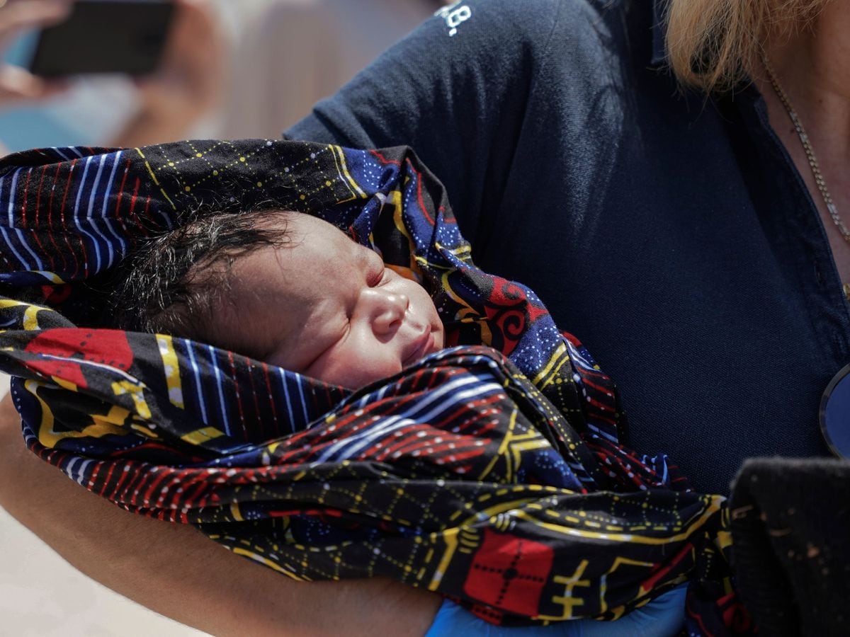 A paramedic holds a newborn boy at Mytilene port, on the north-eastern Aegean Sea island of Lesbos, Greece, on Wednesday June 22 2022