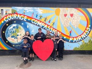 Morda pupils hold their Morda 'big heart' in front of the school's 'Morda Values' rainbow mural. Photo: Morda School.