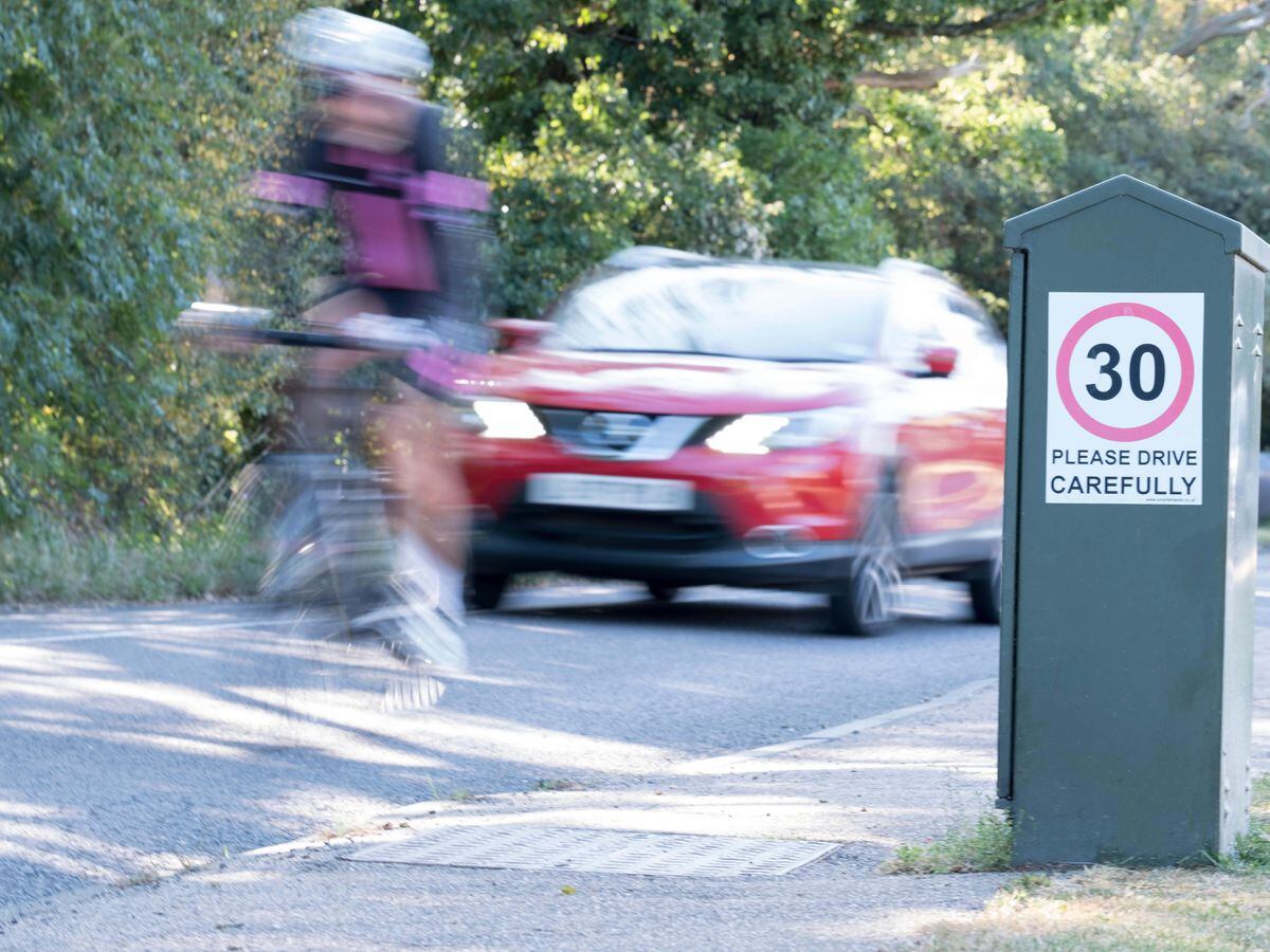 A 30mph sign as a car and a cyclist go past
