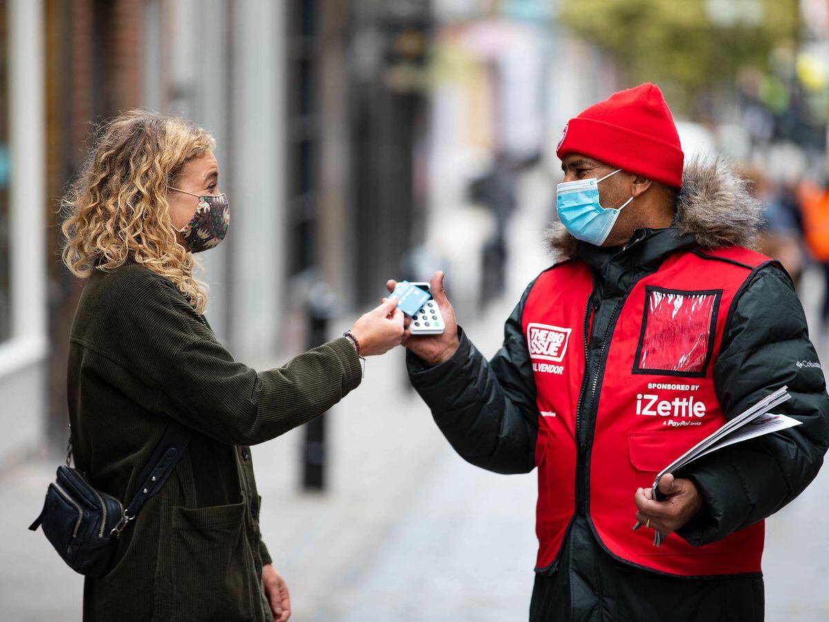 A Big Issue vendor takes a contactless card payment