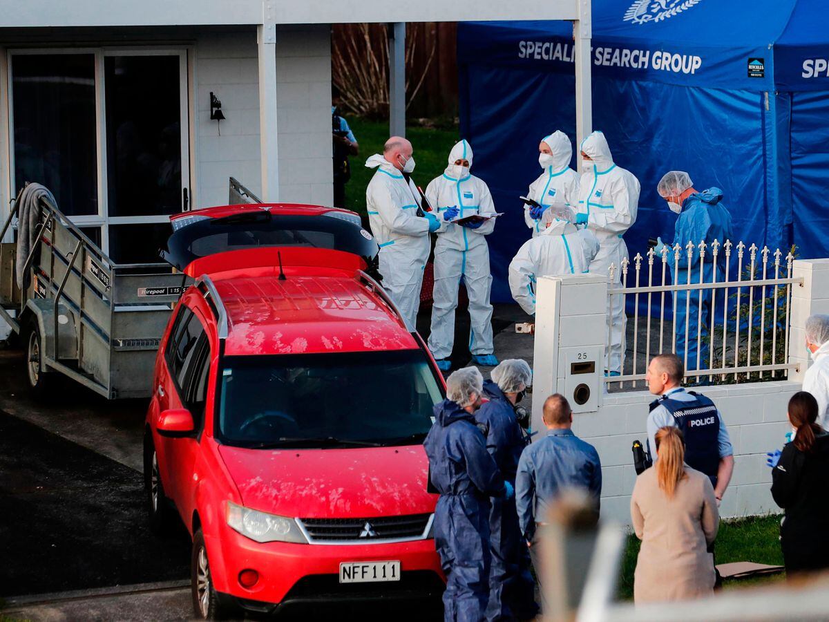 New Zealand police investigators work at a scene in Auckland after bodies were discovered in suitcases