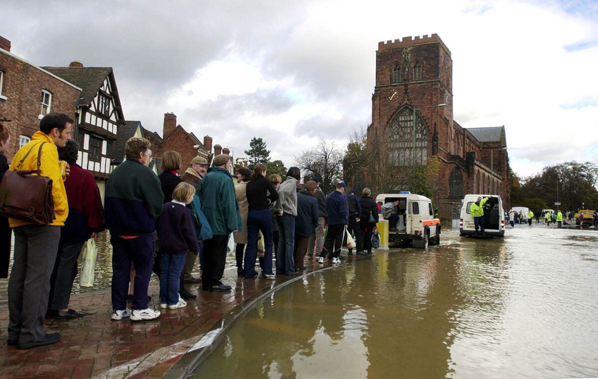 Shrewsbury residents queue on a traffic island as they wait to be ferried through floodwaters by emergency service vehicles on October 31, 2000. 