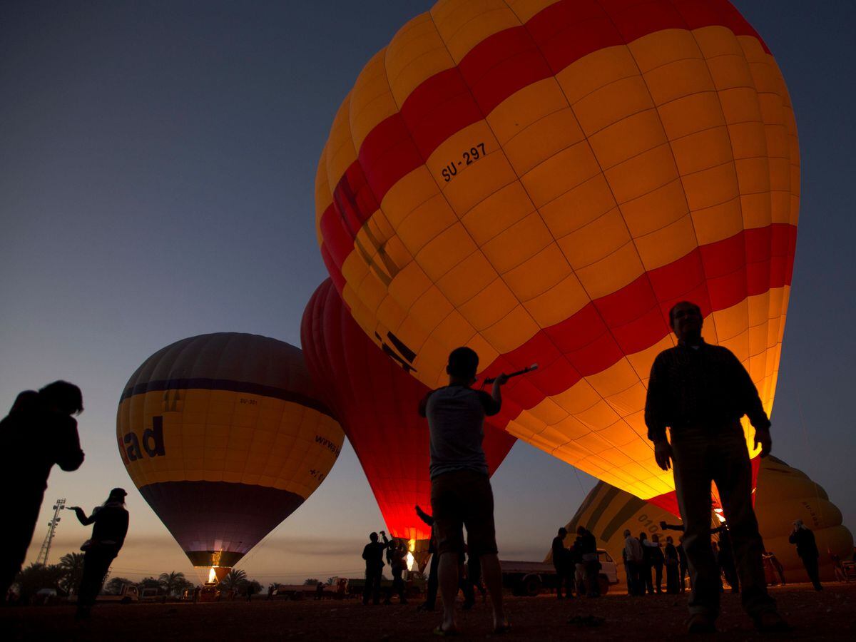 Tourists see hot air balloons ready for take off at dawn on the west bank of the Nile in Luxor, Egypt