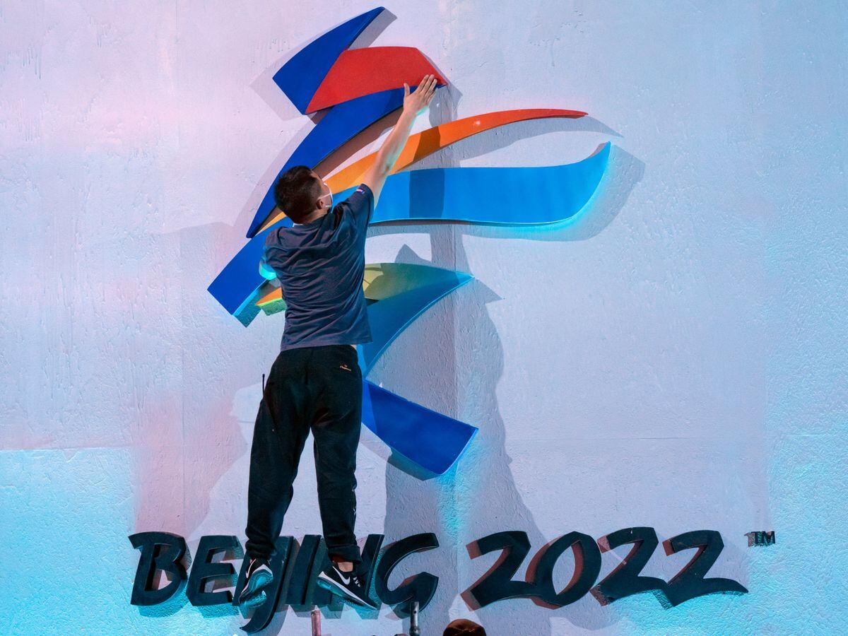 A crew member leaps to fix a logo for the 2022 Beijing Winter Olympics before a launch ceremony to reveal the motto for the Winter Olympics and Paralympics in Beijing on Sept. 17, 2021