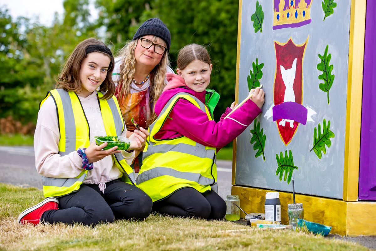 Maisie Reeves, 11, Liz Tool and Emily Harris, 11 decorating the BT cabinets outside Criftins Parish Hall