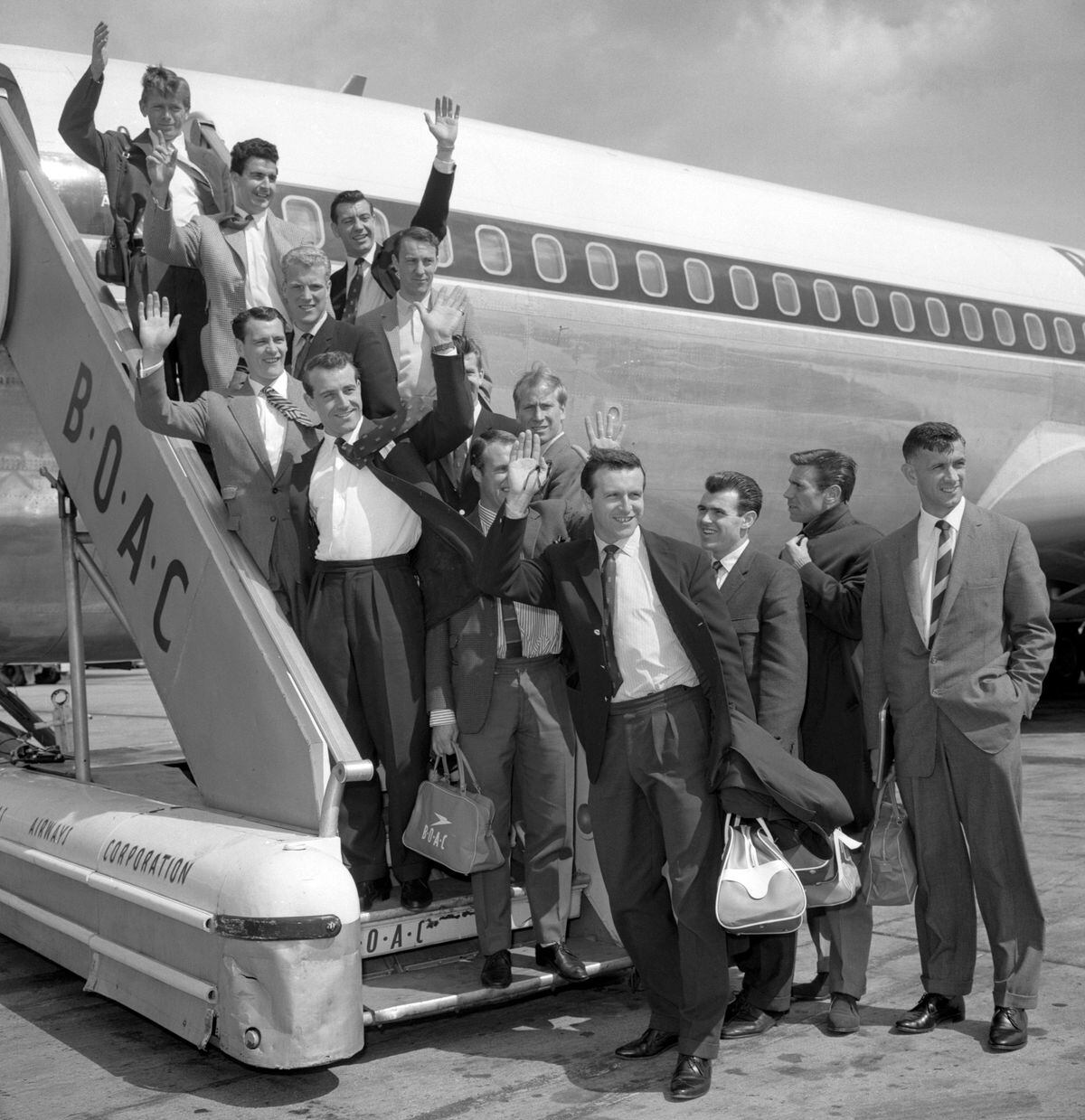 England's World Cup footballers wave before leaving London Airport. From top: Gerry Hitchins, Stan Anderson, Johnny Haynes, Ron Flowers (left), Jimmy Greaves (right), Bobby Robson, Peter Swan, Ron Springett (face hidden), Bobby Charlton, Ray Wilson (face hidden), Jimmy Armfield, John Connolly, Alan Peacock and Bobby Smith.