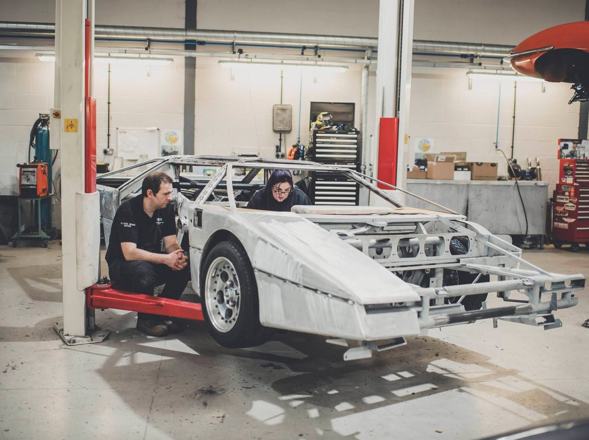 Liz Collings, trim technician, and Luke Martin, panel beater, discuss the dashboard and centre console structure in preparation of returning the car to its original specification.