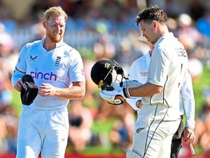 England's Ben Stokes, left, checks on New Zealand's Michael Bracewell after her was struck on the helmet by a ball on the second day of their cricket test match in Tauranga, New Zealand, Friday, Feb. 17, 2023. (Andrew Cornaga/Photosport via AP).