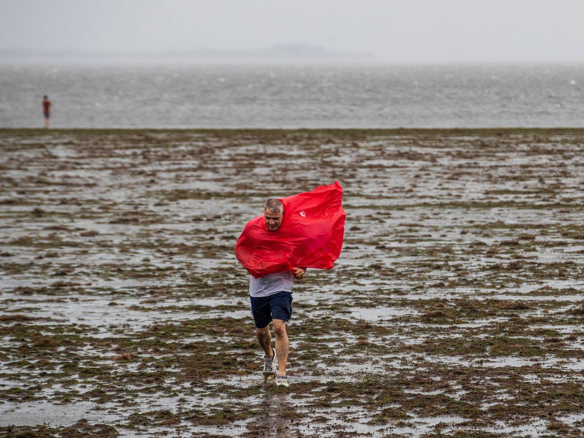 Curious sightseers walk in the receding waters of Tampa Bay due to the low tide and tremendous winds from Hurricane Ian in Tampa Tampa, Fla., Wednesday, Sept. 28, 2022