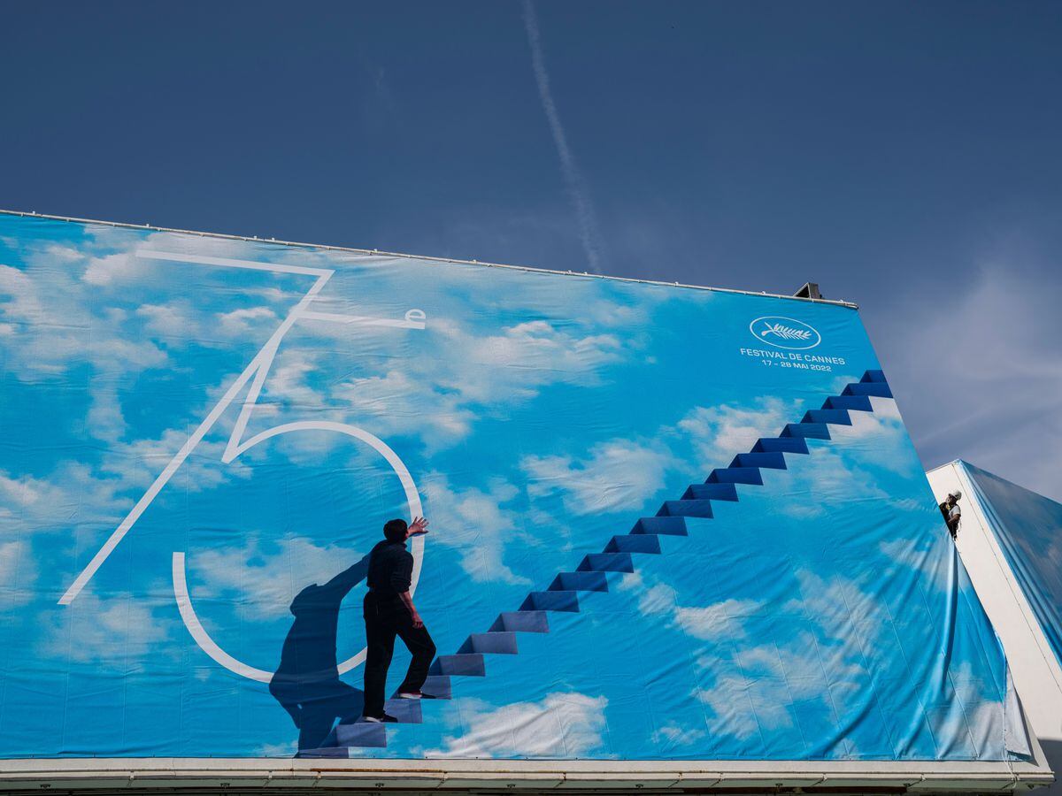 A festival worker places the official poster during preparations for the 75th international film festival in Cannes, southern France