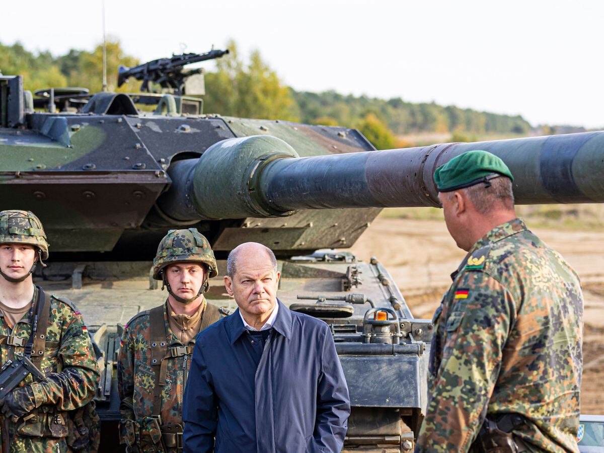 German Chancellor Olaf Scholz stands with German soldiers beside a Leopard 2 main battle tank during a training exercise in Ostenholz in October