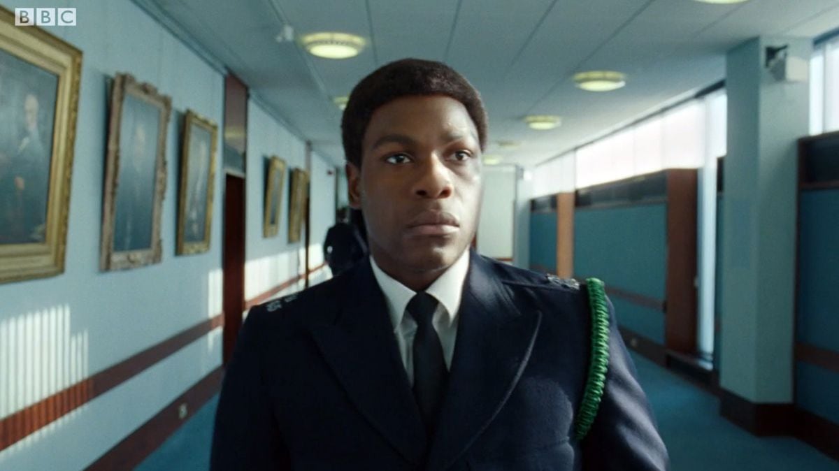 A screenshot still from 'Red, White, and Blue' in the BBC 'Small Axe' series which starred John Boyega as a black man who joins the police force. Broadcast late in 2020, it featured scenes shot at the Shirehall, Shrewsbury, home for Shropshire Council. The Shirehall played the 'part' of a police training college. This picture shows him walking down a corridor of the Shirehall with paintings on the walls - they are actually paintings of former Shropshire council chairmen.