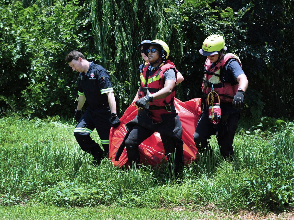 Rescuers carry the body of a flood victim retrieved from the Jukskei river in Johannesburg