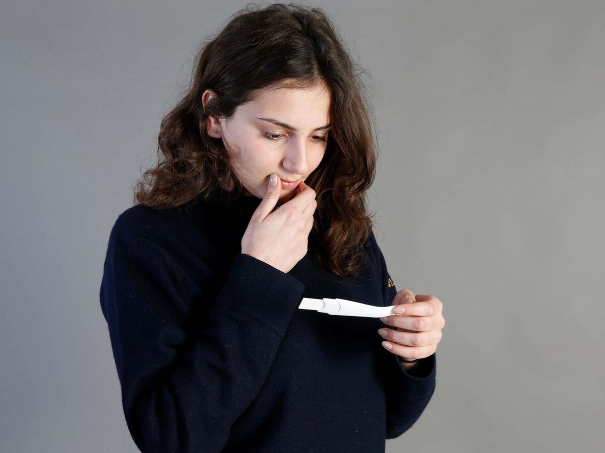 A young woman, posed by a model, with a pregnancy test