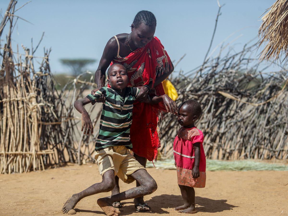 A mother helps her malnourished son stand after he collapsed near their hut in the village of Lomoputh in northern Kenya on Thursday May 12 2022
