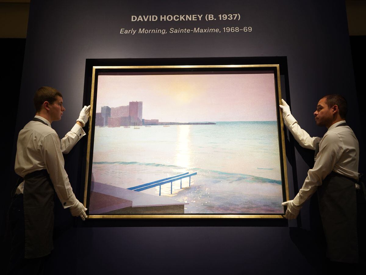 Art handlers holding David Hockney’s, Early Morning, Sainte-Maxime, during a photo call for highlights from Christie’s forthcoming evening sales, their 20th/21st Century and A Place With No Name: Works from the Sina Jina Collection sales, at Christie’s in London