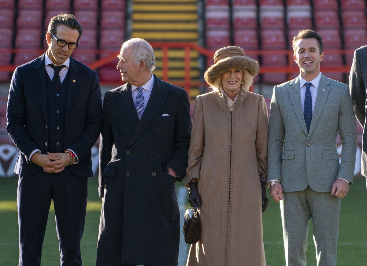 King Charles III and the Queen Consort during their visit to Wrexham Association Football Club's Racecourse Ground, meeting owners and Hollywood actors, Ryan Reynolds (left) and Rob McElhenney (right), and players to learn about the redevelopment of the club, as part of their visit to Wrexham. Picture date: Friday December 9, 2022.