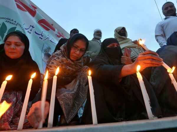 Women light candles during a prayer ceremony for victims of Monday's suicide bombing inside a mosque in Peshawar, Pakistan