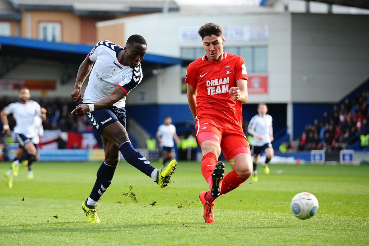 Dan Udoh of AFC Telford shoots under pressure from Dan Happe of Orient during the FA Trophy Semi Final fixture between AFC Telford United and Leyton Orient at the New Bucks Head