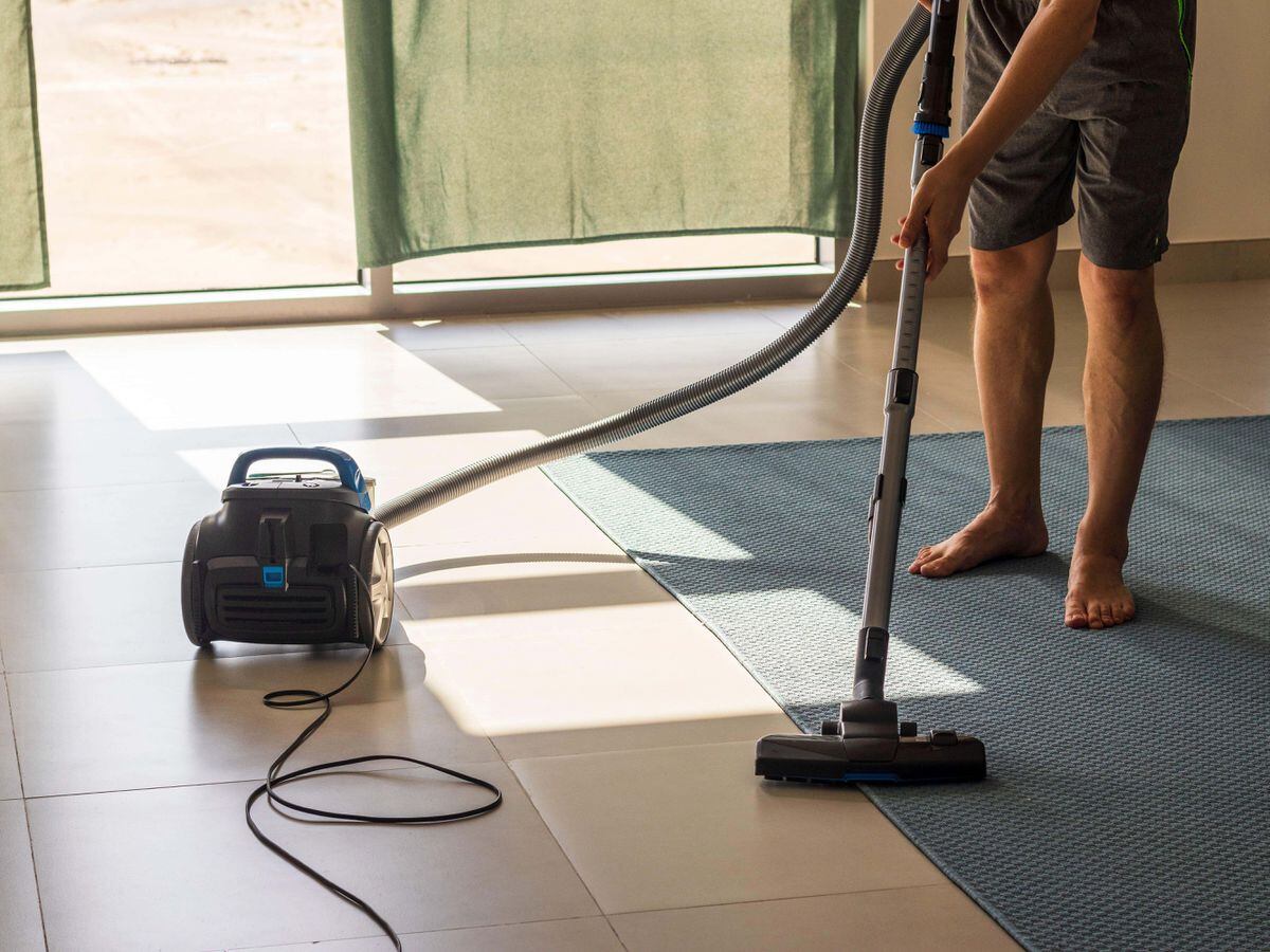A man vacuuming a rug