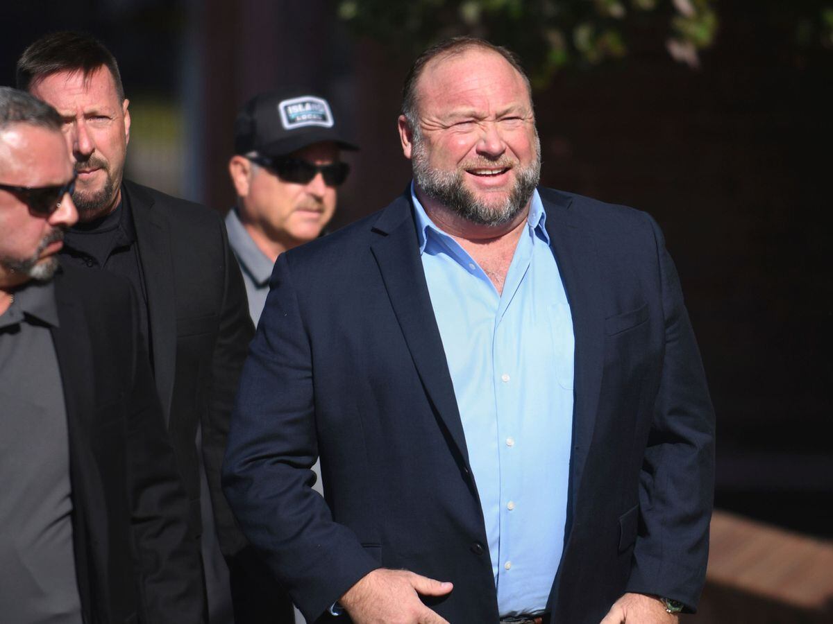 Alex Jones, right, enters court with members of his security team