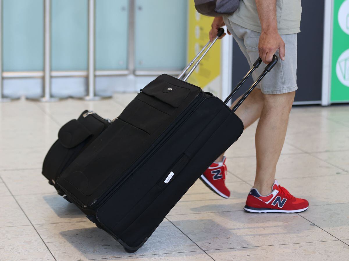 An airline passenger pulls a suitcase