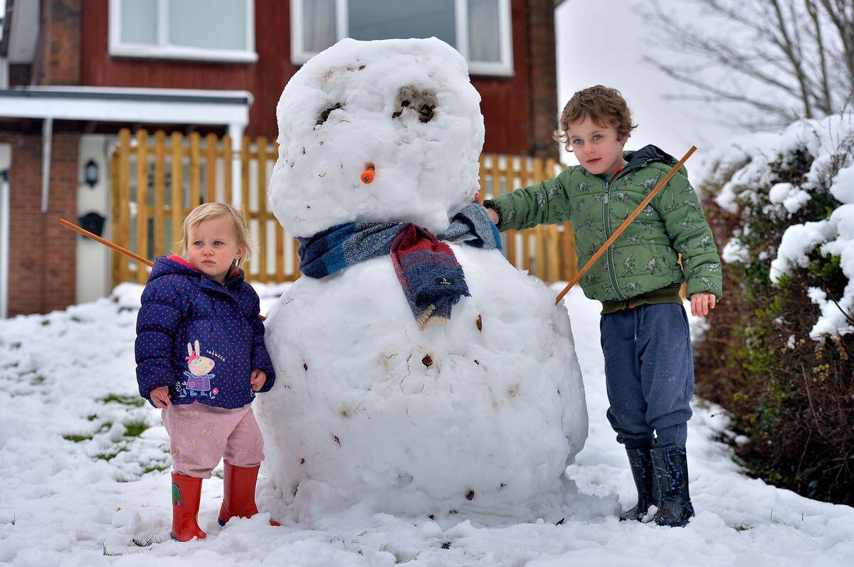 Grace (two) and Joey (four) Price and their snowman in St George's