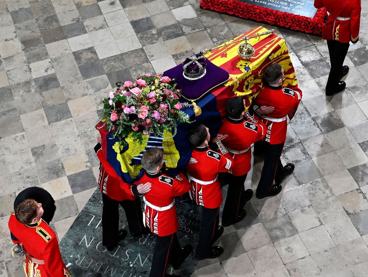 The coffin of Queen Elizabeth II with the Imperial State Crown resting on top is carried by the Bearer Party into Westminster Abbey