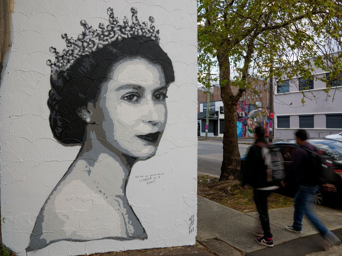 A pedestrian walks past a portrait of Queen Elizabeth II that was installed on a shop wall following her death in Sydney, Australia