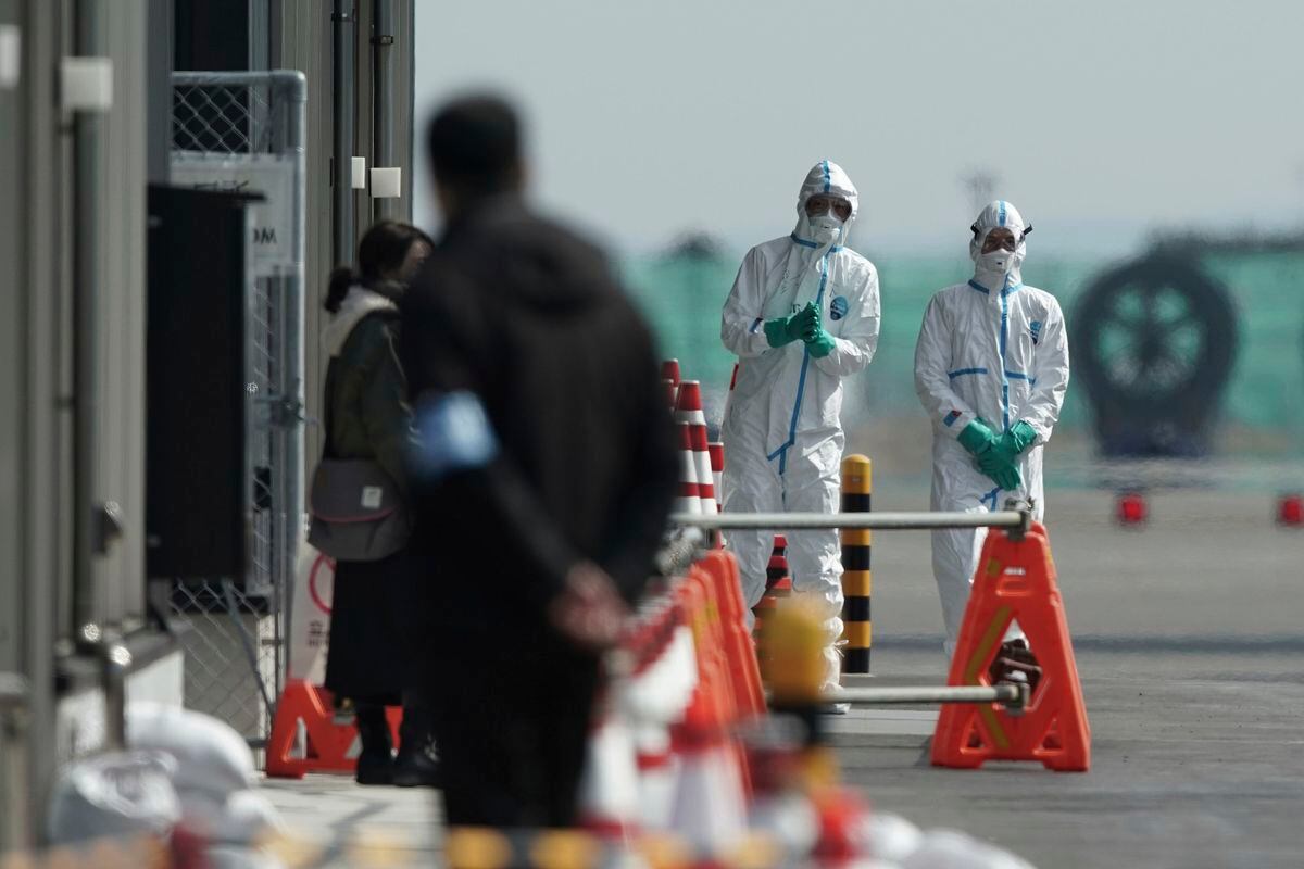 Officials in protective suits talk near the cruise ship