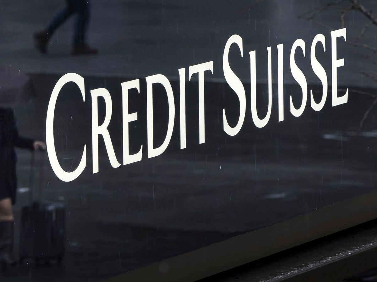 A woman walks past a logo of the Swiss bank Credit Suisse in Zurich