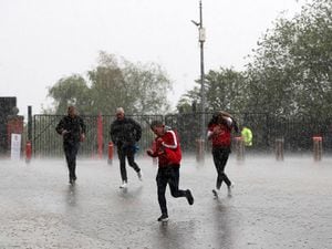 Manchester United fans race to the ground in the heavy rain before the Premier League match at Old Trafford