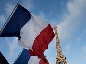 French flags fly in front of the Eiffel Tower