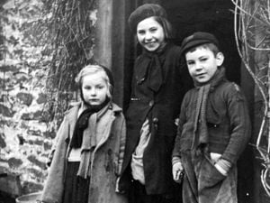 June's refugee pal Maria, centre, flanked by two other Hoorne children, Gabriel, left, and August, at the door of their cottage in Chesterton