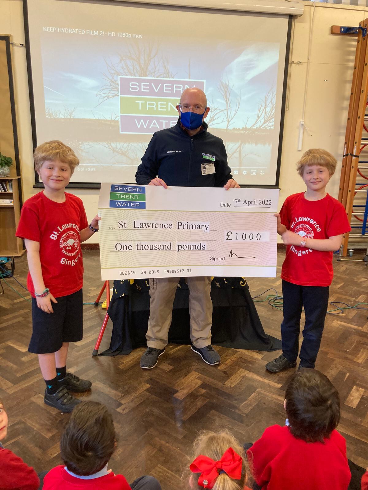 Severn Trent's Chris Harper hands over a cheque to St Lawrence Primary School pupils and twins Toby and Jacob Cleaton
