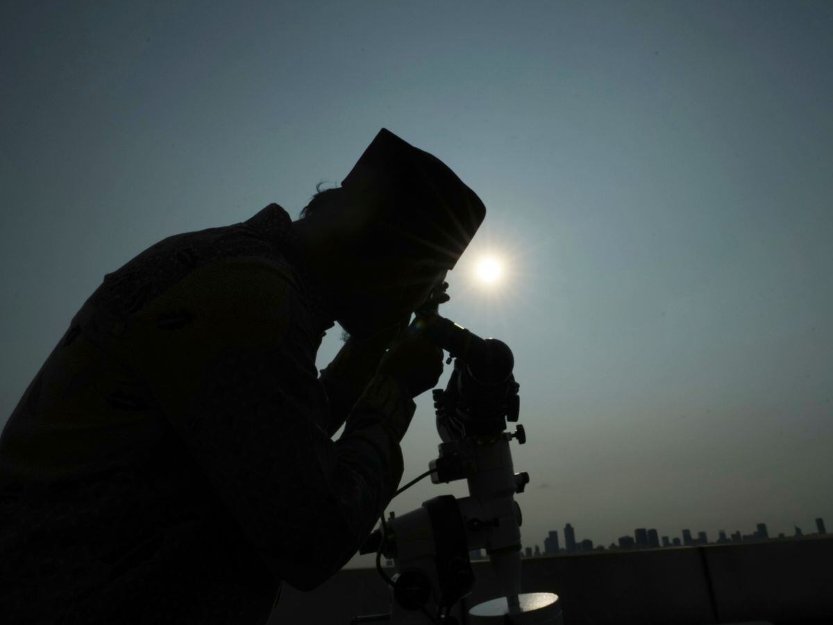 An official uses a telescope to scan the horizon for a crescent moon that will determine the beginning of the holy fasting month of Ramadan in Jakarta, Indonesia