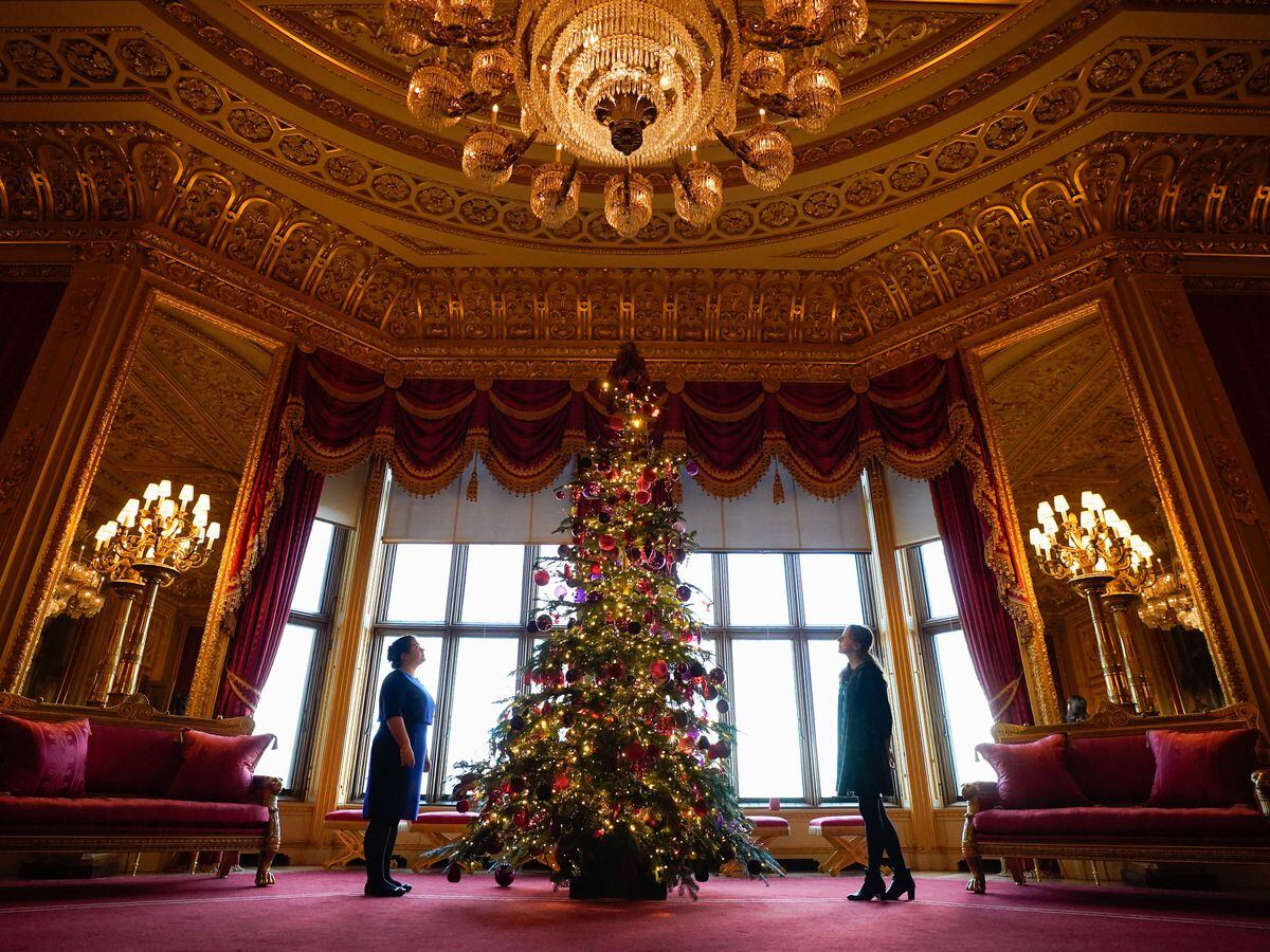 Members of the Royal Collection Trust look up at a Christmas tree on display in the Crimson Drawing Room