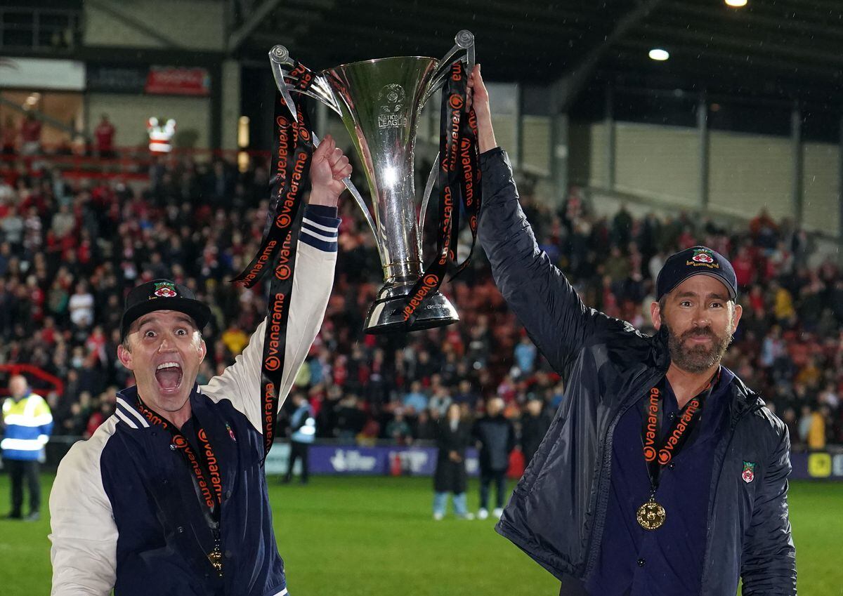 Wrexham co-owners Rob McElhenney and Ryan Reynolds celebrate with the trophy following promotion to the EFL following the Vanarama National League match at The Racecourse Ground, Wrexham. 