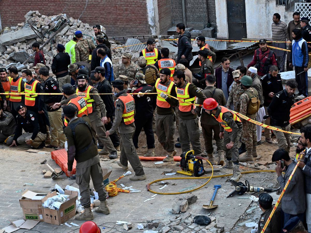 Security officials and rescue workers gather at the site of suicide bombing, in Peshawar, Pakistan