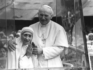  Pope John Paul II holds his arm around Mother Teresa as they ride in the Popemobile outside the Home of the Dying in Calcutta, India in February 1986 