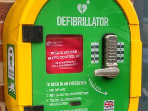 A defibrillator cabinet containing both an automated external defibrillator and a bleed control kit.