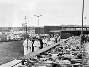 nostalgia pic. Shrewsbury. "The clergy and choir from the Church of the Holy Spirit in Harlescott winds slowly through the Shrewsbury Smithfield Market yesterday as part of the annual rogational day service at Shrewsbury," reads the caption pasted on the back of this print in the Express and Star picture archive. It was taken on May 5, 1964, and published on May 6, 1964. The print has the Express and Star copyright stamp and the photographer was Bob Craig. Print copied in situ at the E&S picture archive at Queen Street (in the basement) on October 27, 2021. Shrewsbury cattle market. Shrewsbury livestock market. Prayers. Religion. Library code: Shrewsbury nostalgia 2021..