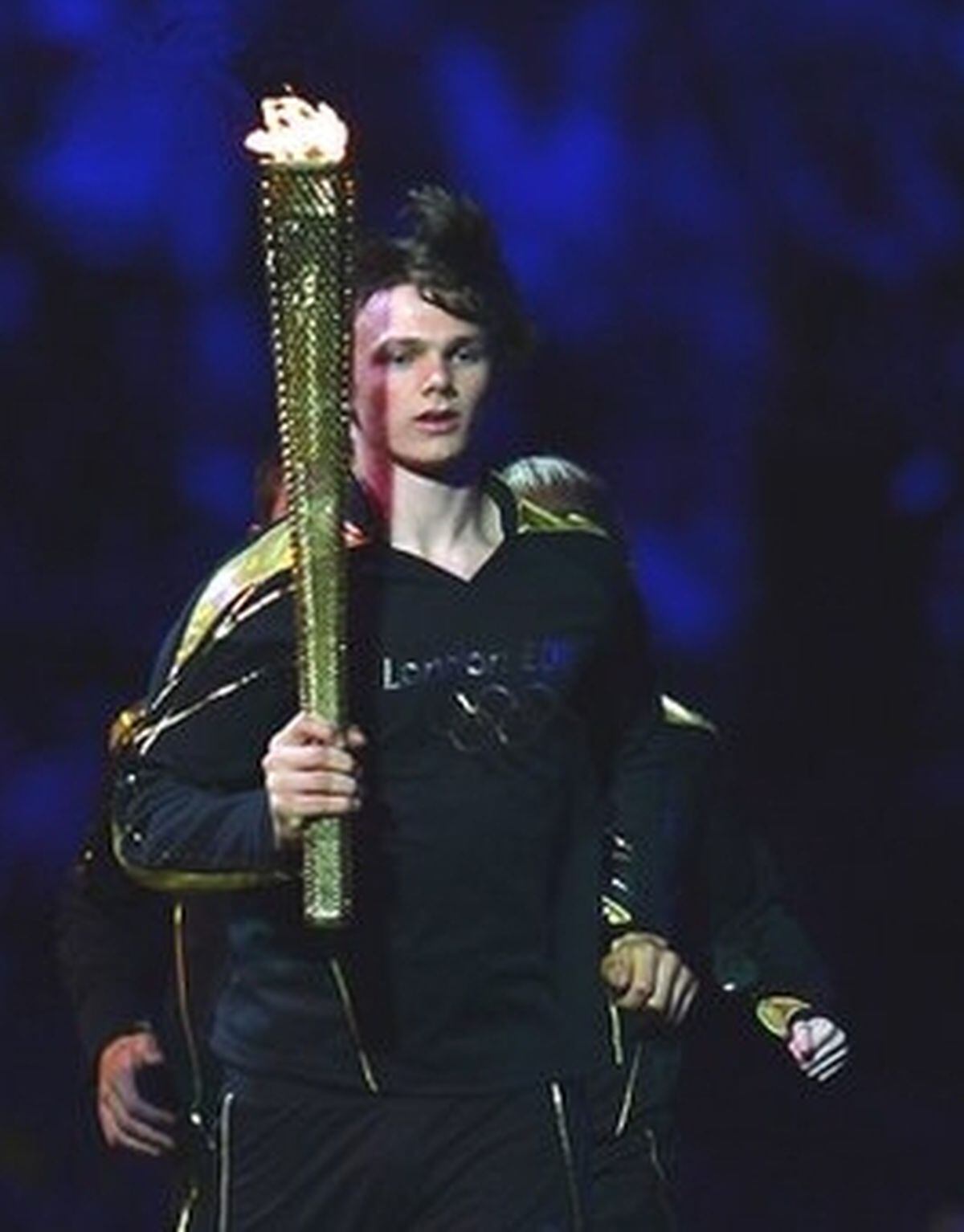 Aidan Reynolds carries the Olympic flame in the arena