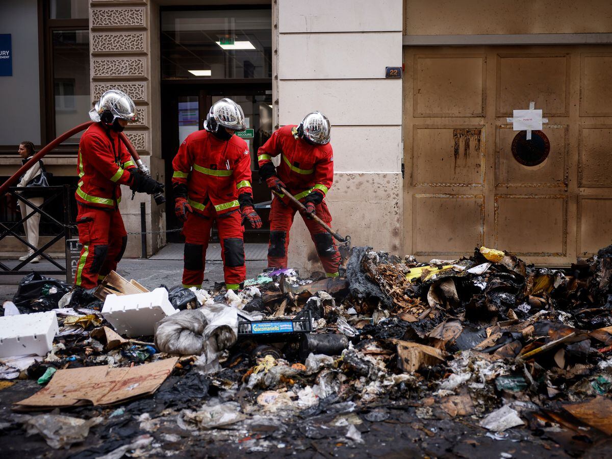 Firefighters controlling the remains of a rubbish fire from Thursday night's protests in Paris against the retirement Bill